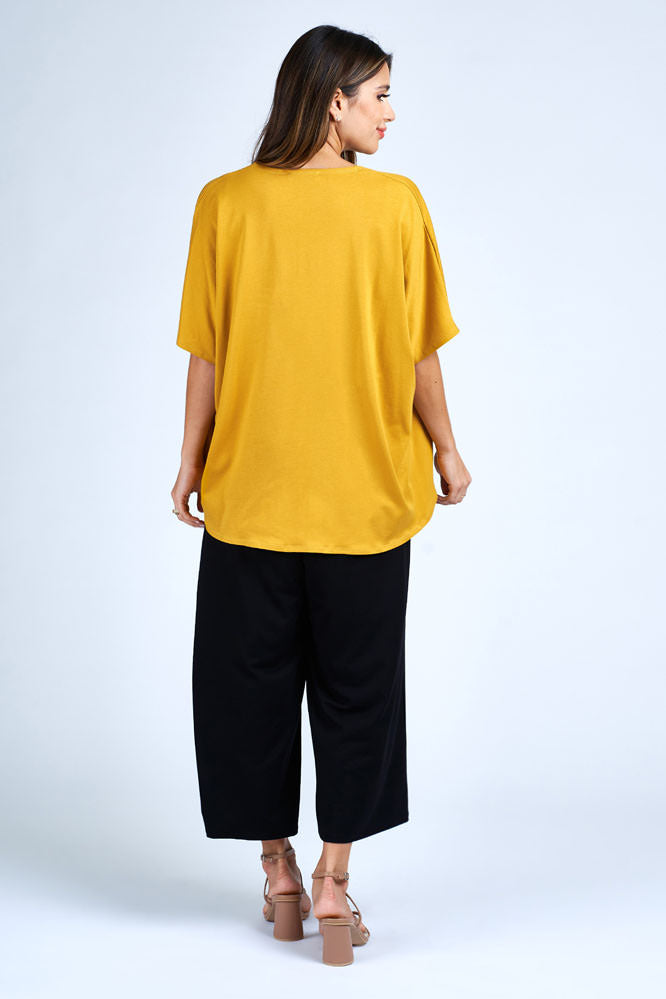 Woman wearing yellow cardigan over black dress.