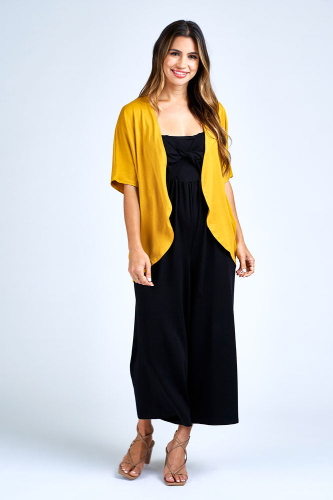 Woman wearing yellow cardigan over black dress.