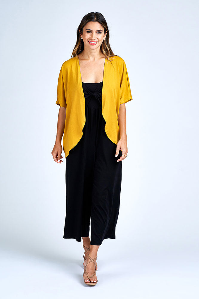 Woman wearing yellow cardigan over black dress.