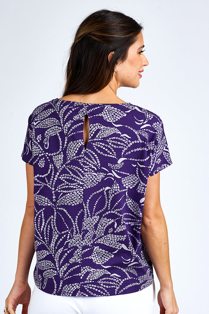 Woman wearing a purple and white short sleeve top.