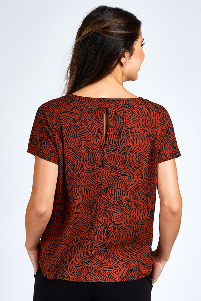 Woman wearing an orange and black short sleeve top.