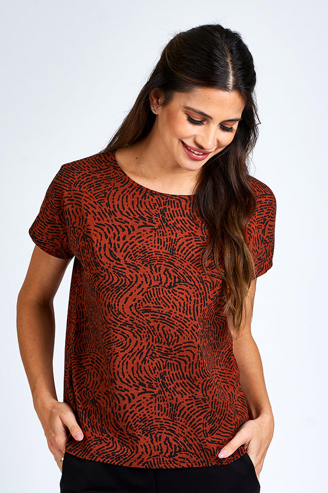Woman wearing an orange and black short sleeve top.