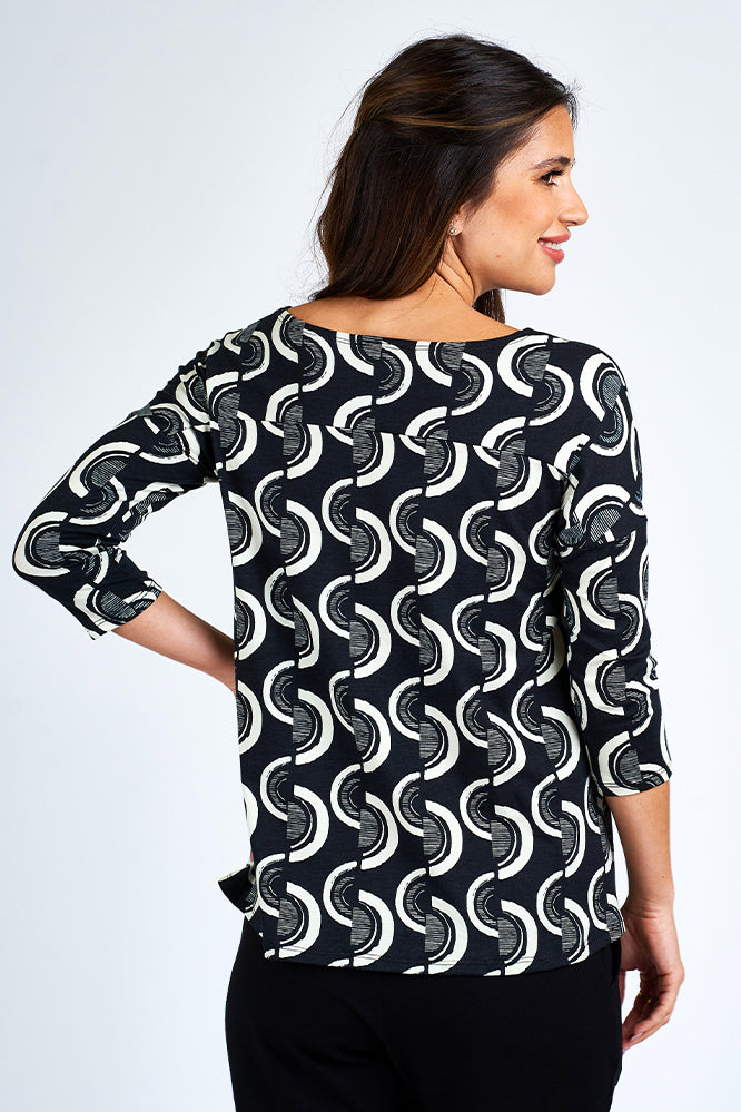 Woman wearing black and white 3/4 sleeve top and black shorts.