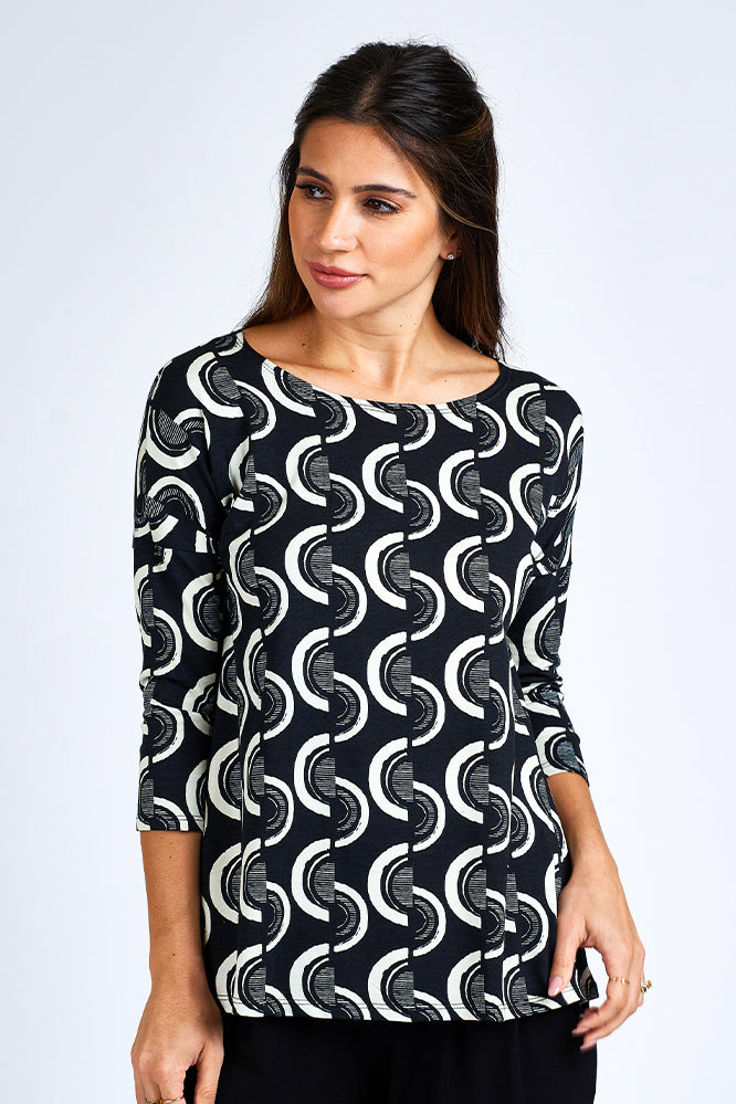 Woman wearing black and white 3/4 sleeve top and black shorts.