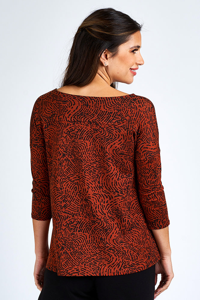 Woman wearing orange and black 3/4 sleeve top and black shorts.