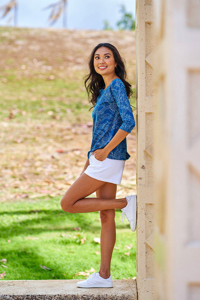 Woman wearing blue and white 3/4 sleeve top and white shorts.