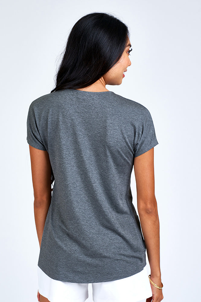 Woman wearing grey short sleeve top.