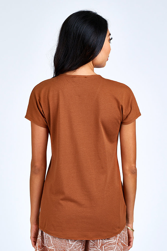 Woman wearing rust short sleeve top.