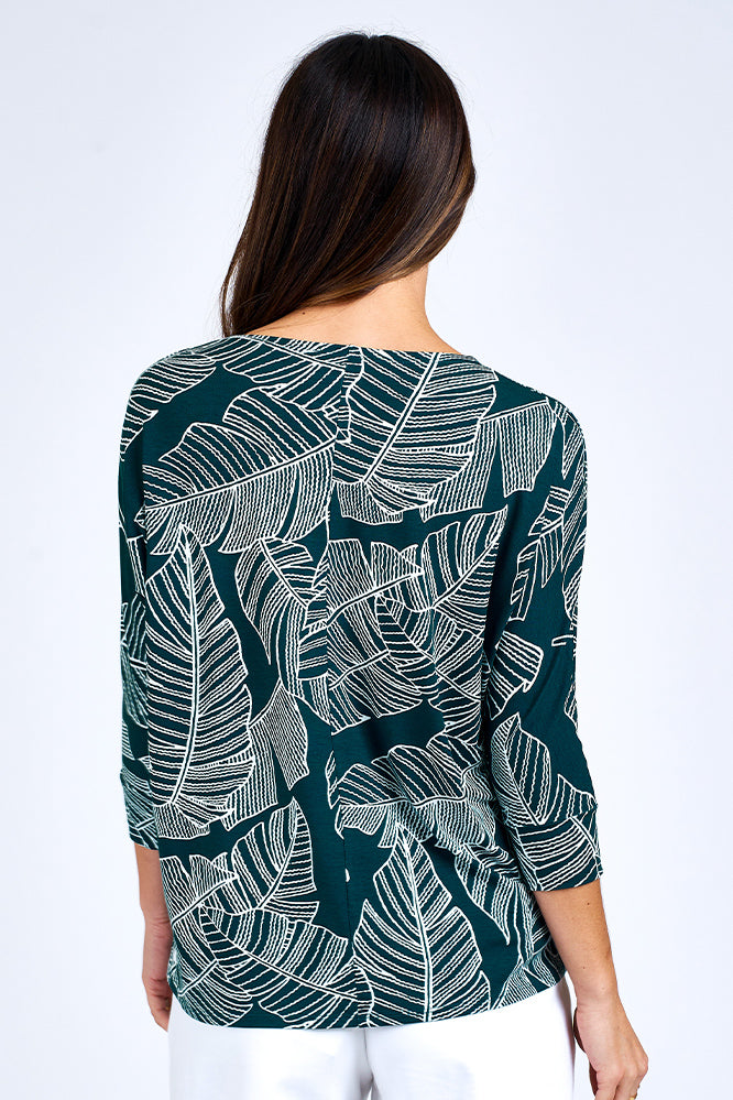 Woman wearing forest green 3/4 sleeve top and white shorts.