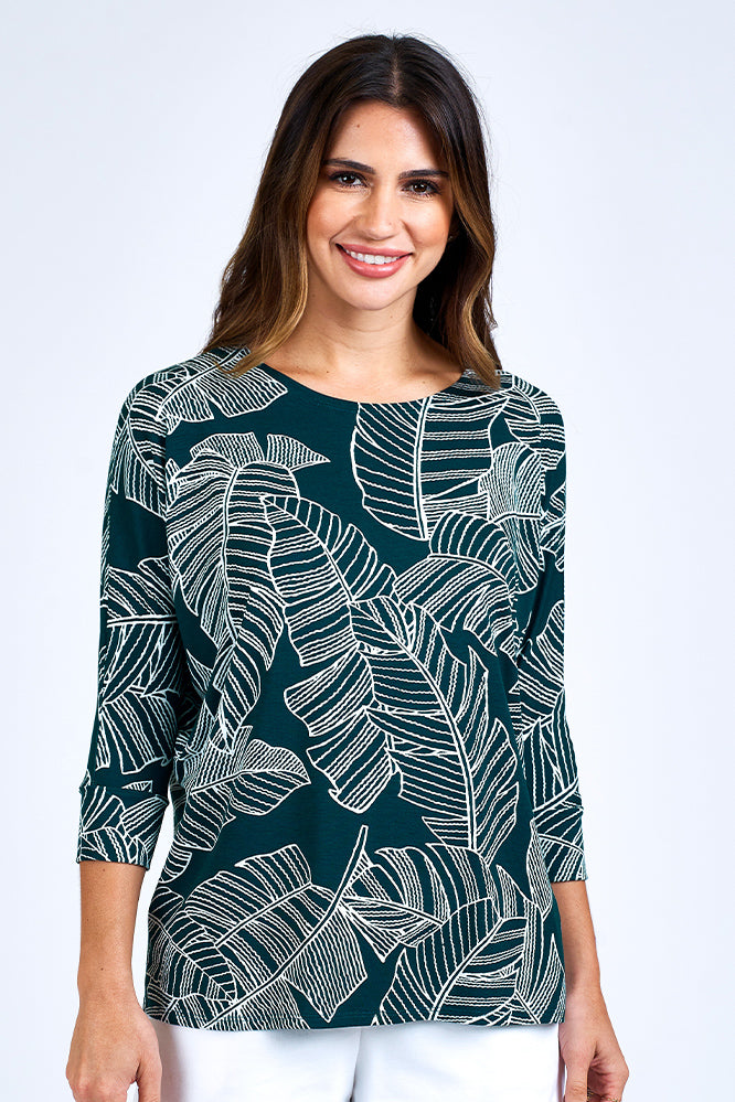 Woman wearing forest green 3/4 sleeve top and white shorts.