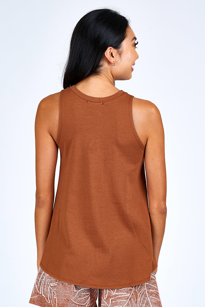 Woman wearing rust and white shorts and rust color tank top.
