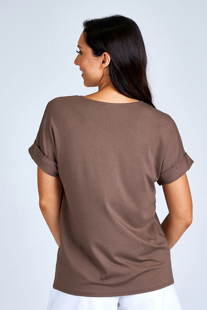 Woman wearing light brown short sleeve top.