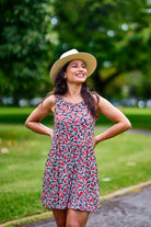 Woman wearing hat and pink print dress.