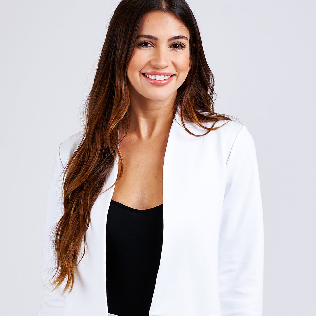 Woman wearing white jacket and black tank top.